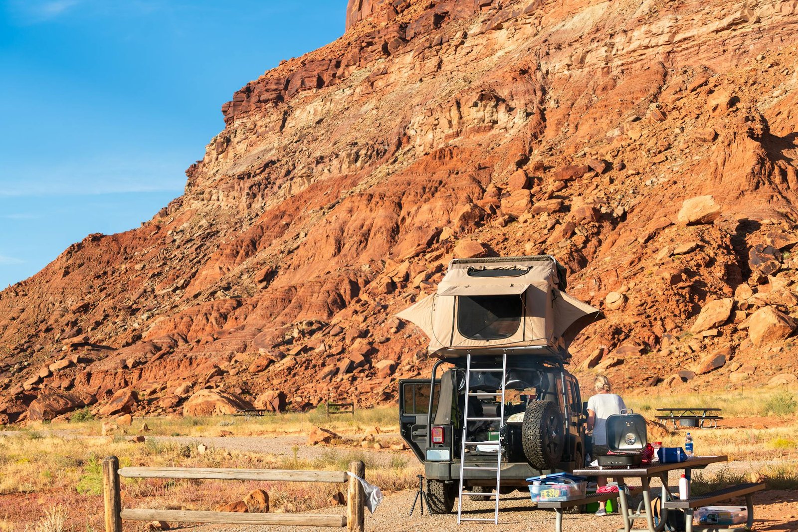 Explore the rugged beauty of Utah's desert with a campsite set against stunning red rock cliffs.